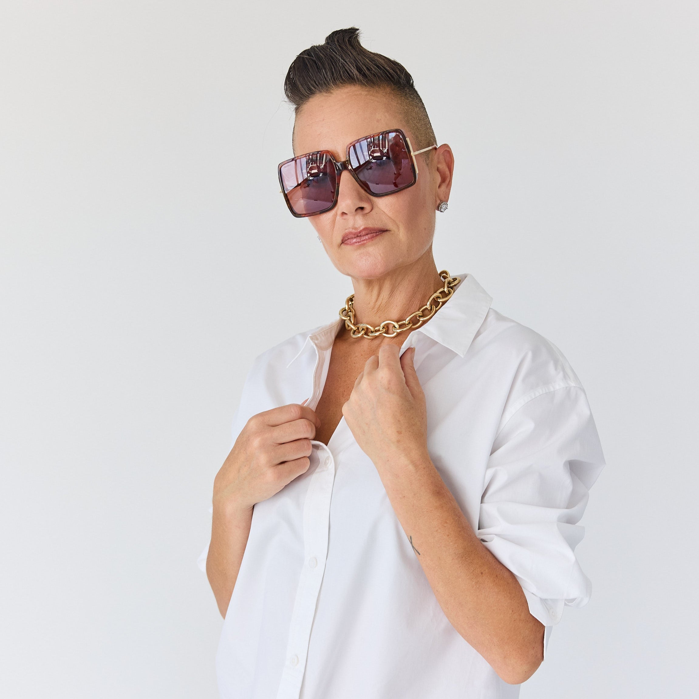 stylish woman in a oversized white shirt and gold chain necklace